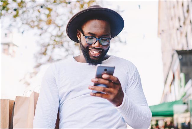 A person smiling while looking at a smartphone.