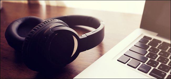 Bluetooth headphones laying next to a Mac
