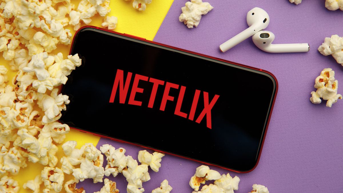 Netflix logo on an iPhone and next to AirPods and popcorn