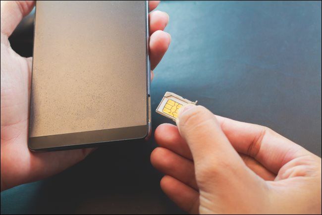 A hand inserting a SIM card into a smartphone.