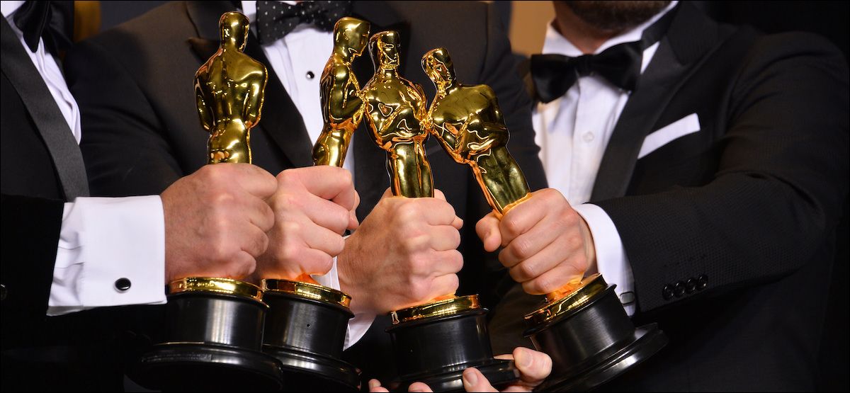 Three men holding Oscar awards