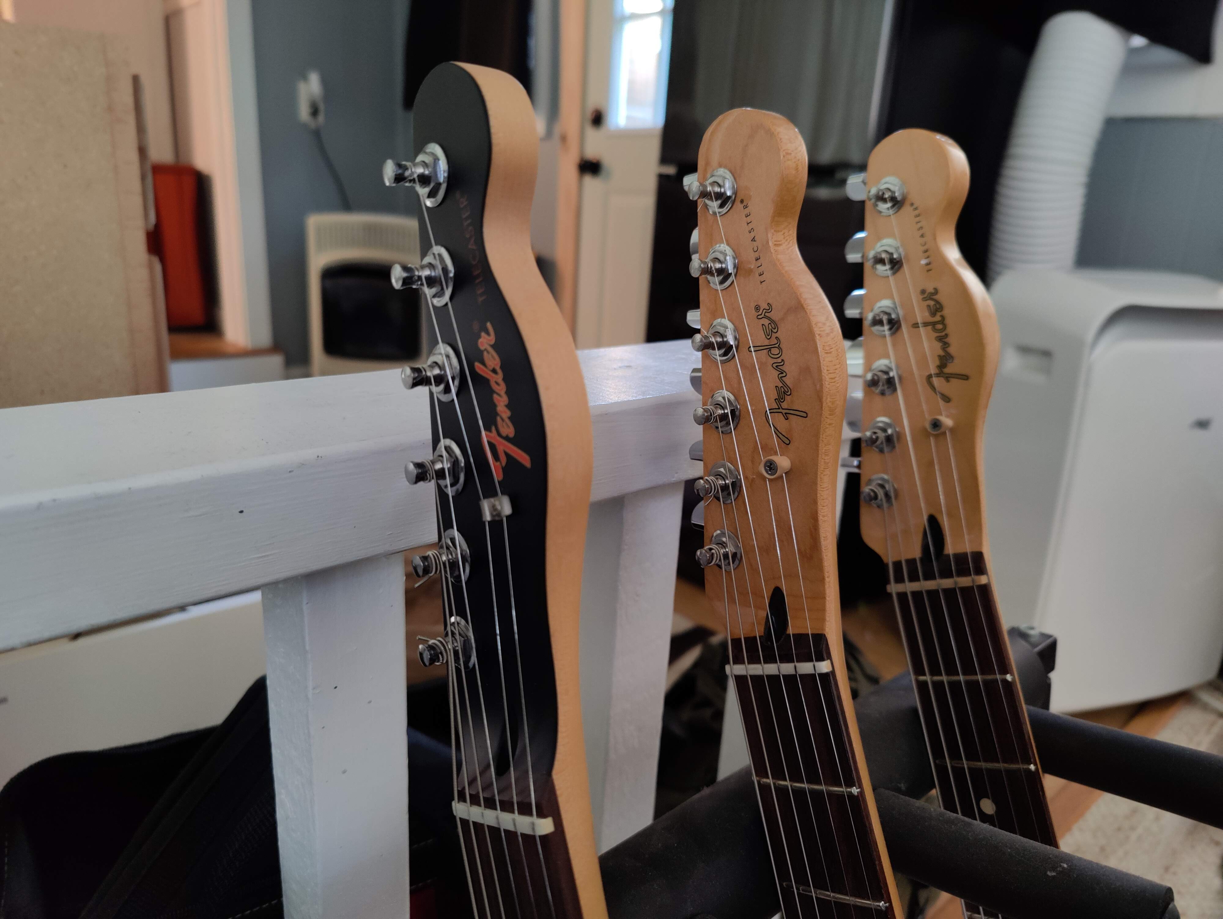 OnePlus 9 Pro Camera Sample: A closeup of three Fender Telecaster guitar headstocks shot indoors with the main camera