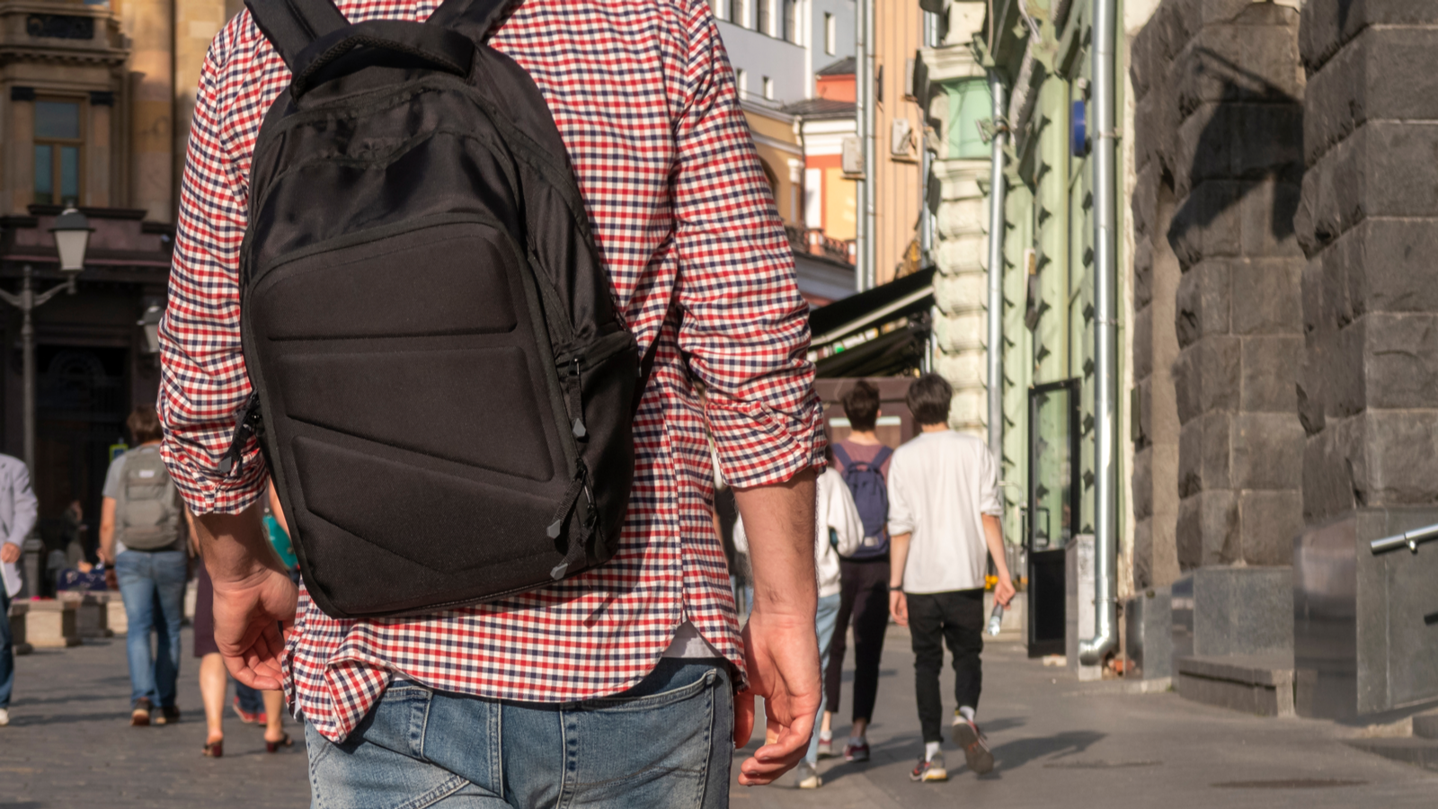 Person walking down a city street wearing a black backpack