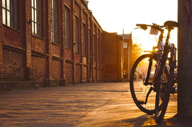 A bicycle parked on a city sidewalk at sunset.