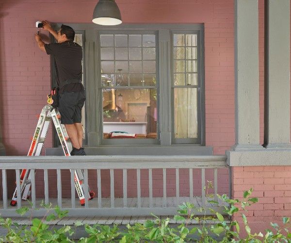 Man installing camera on outside of home