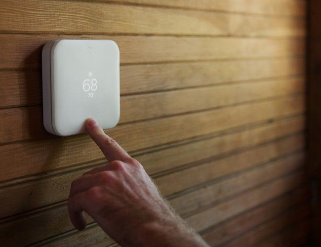 Square white thermostat on wooden wall