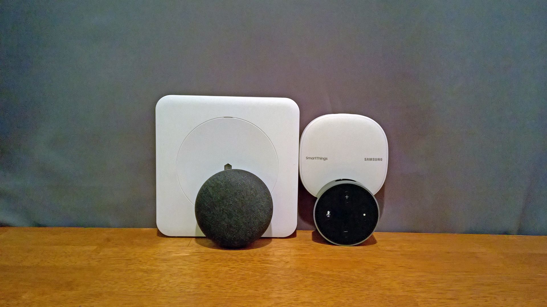 A Nest mini and Echo dot in front of a Wink and SmartThings hub