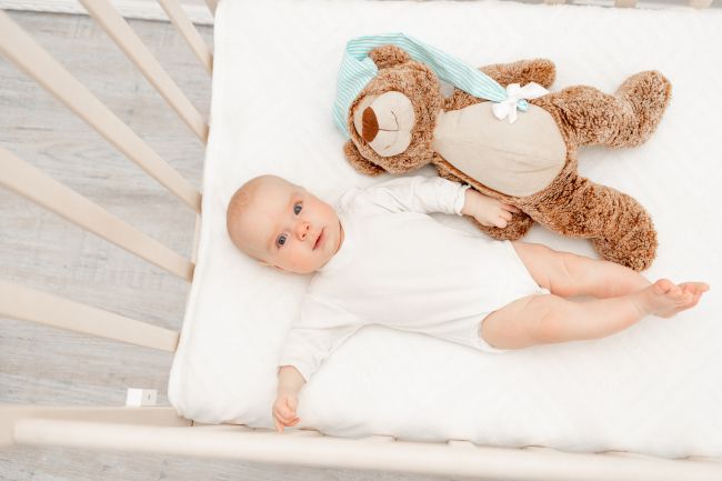 Baby in crib with teddy bear