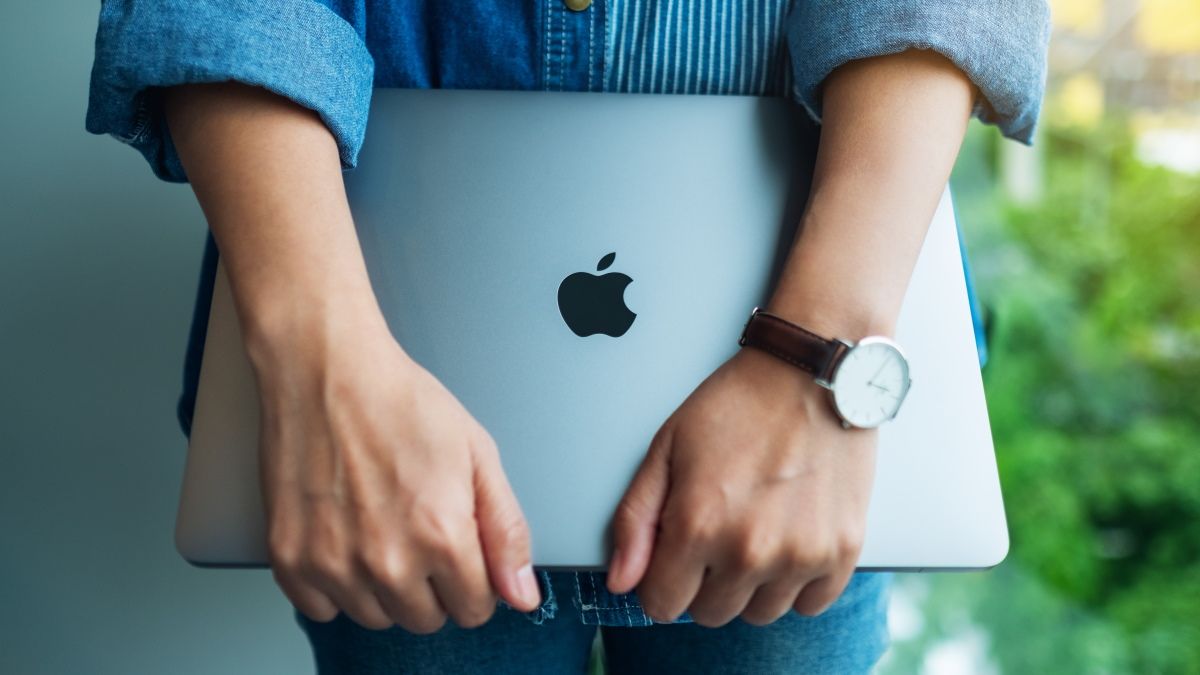 A woman holding an Apple MacBook Pro.