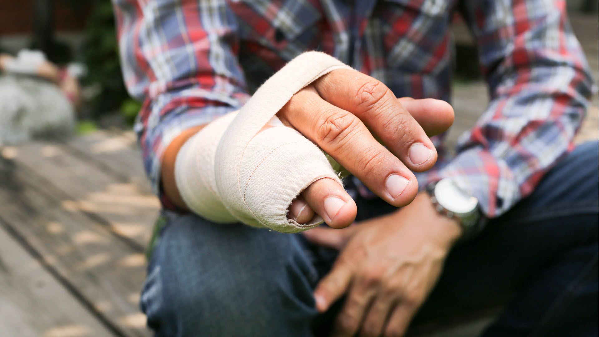 A man with his broken ring finger and pinky wrapped in a cast.