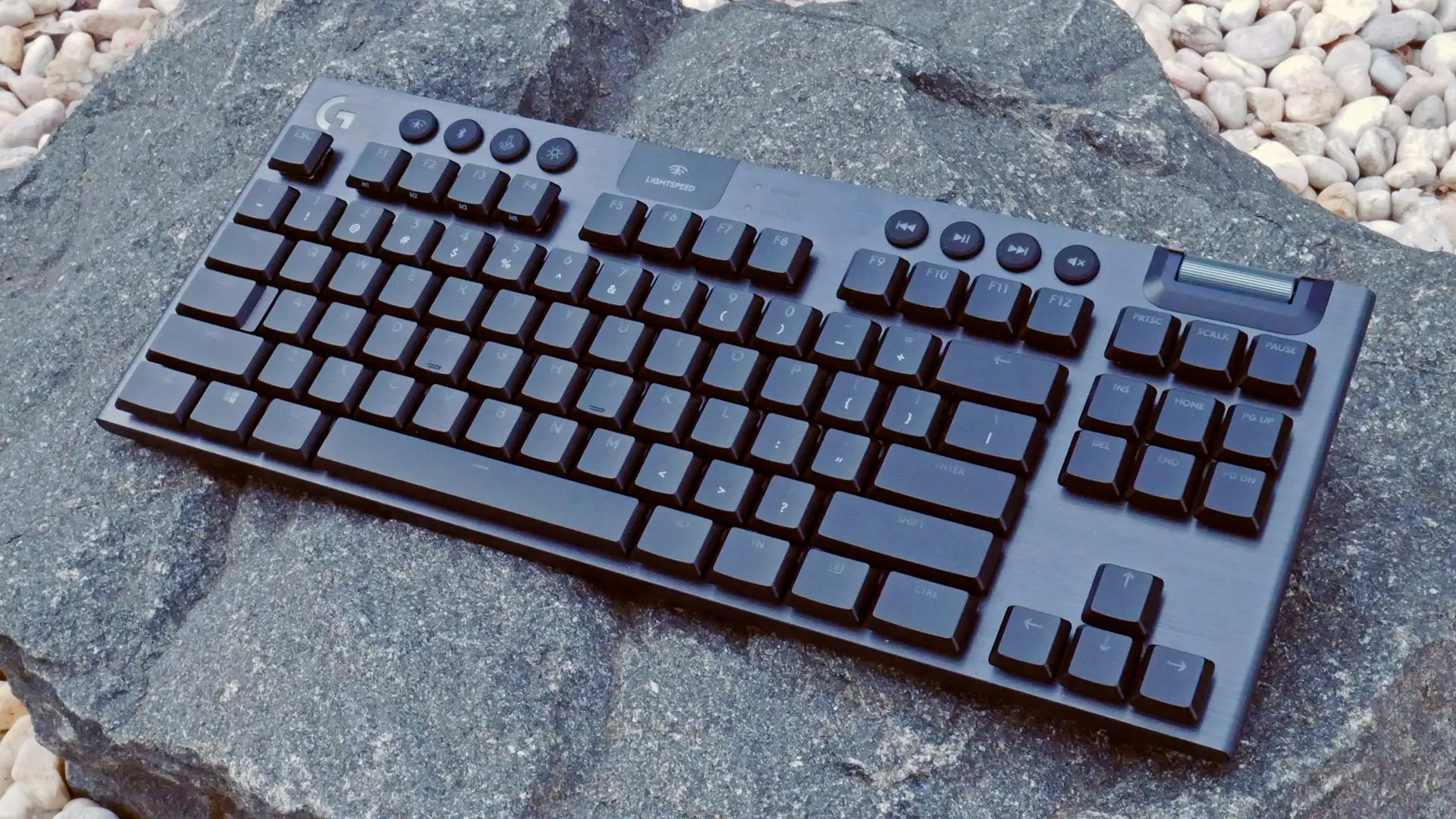 Logitech G915 TKL keyboard sitting on a rock