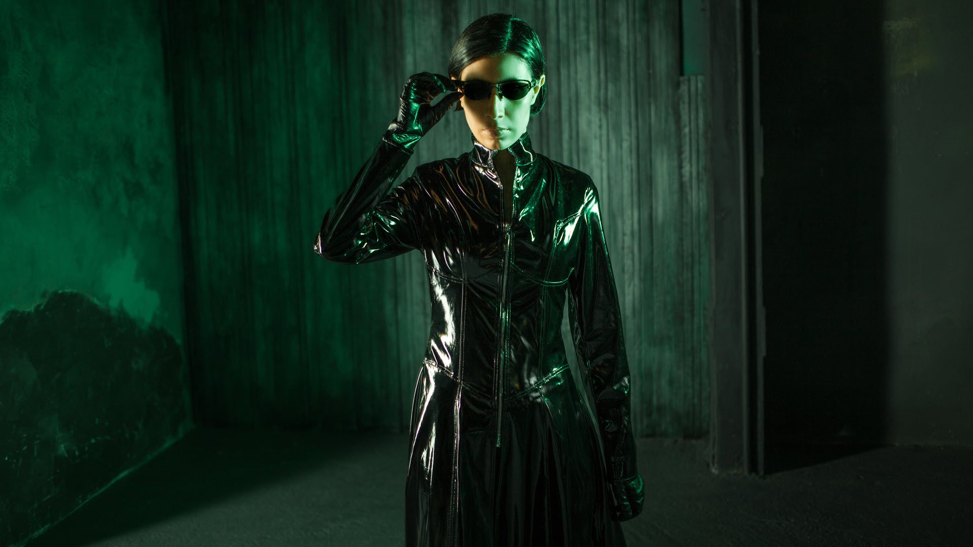 A young woman dressed like the character Trinity from 'The Matrix' surrounded by green hues.