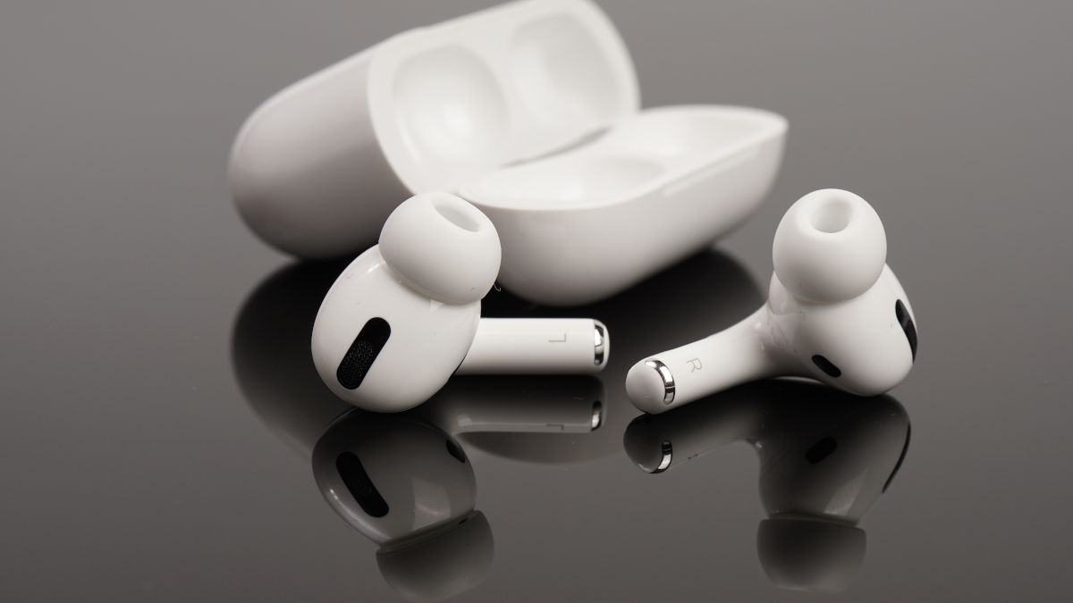 Apple Airpods and case on a dark reflective surface