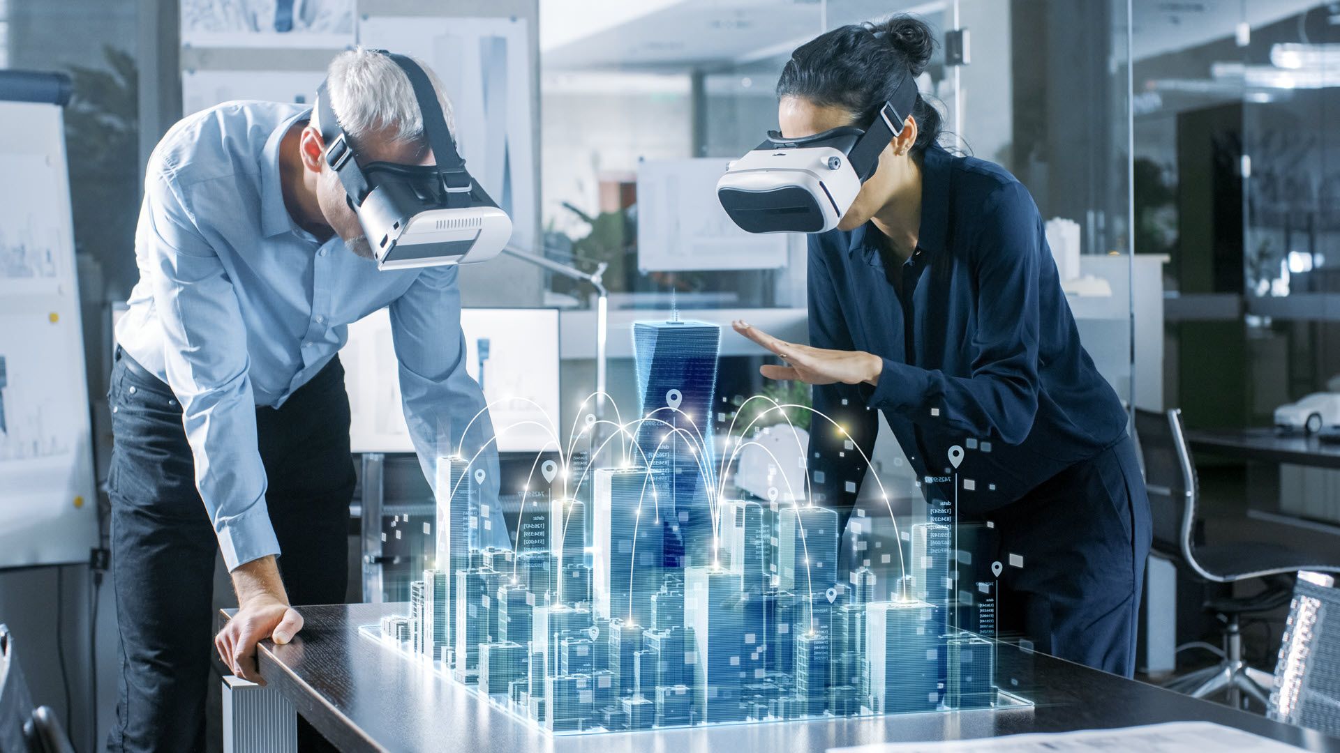 Two people in VR sets staring at an virtual architecture schematic of a city.