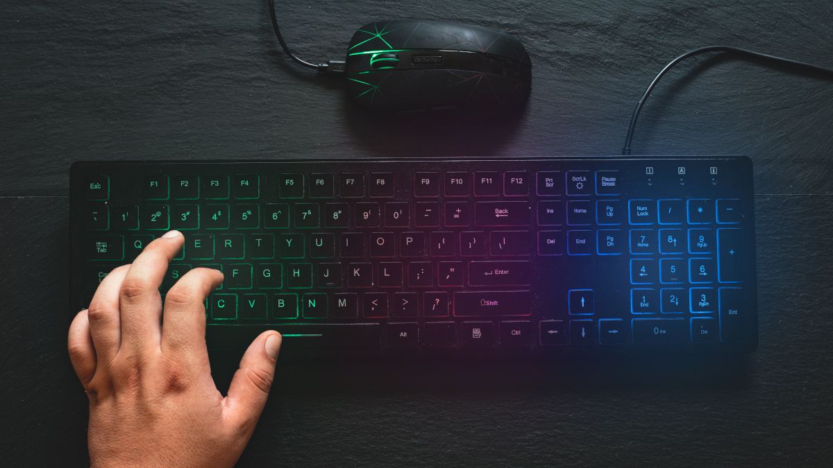 RGB colored keyboard and mouse with hand on the keyboard