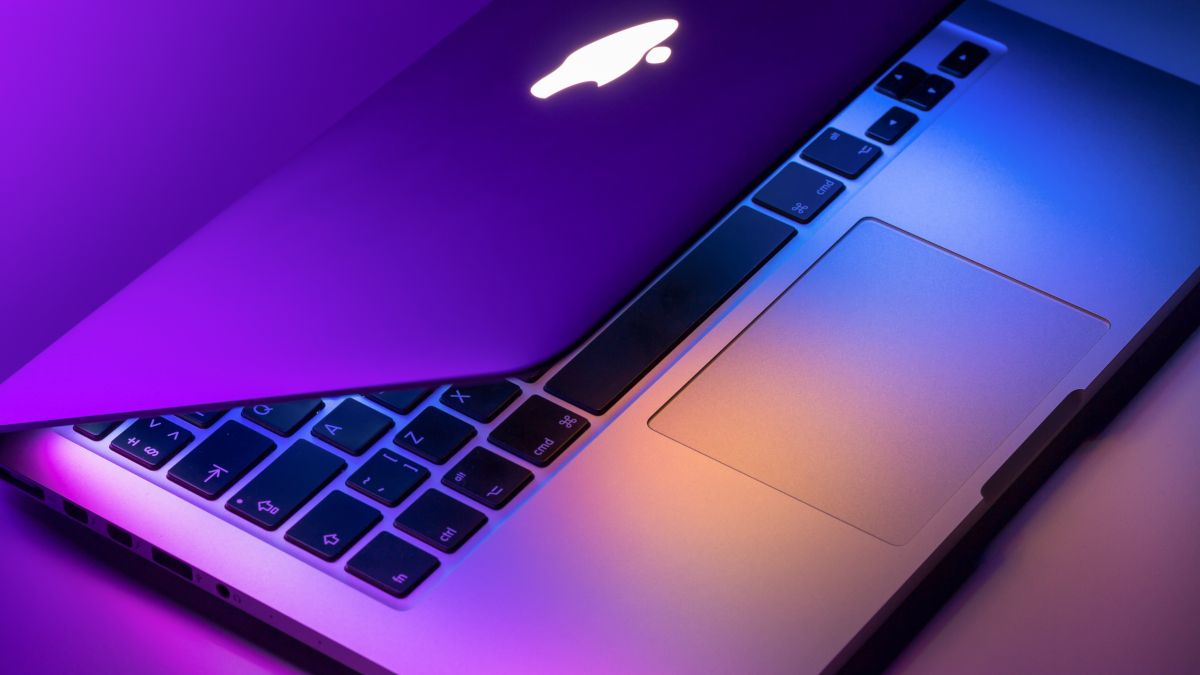 MacBook Pro partially open in purple and blue lights