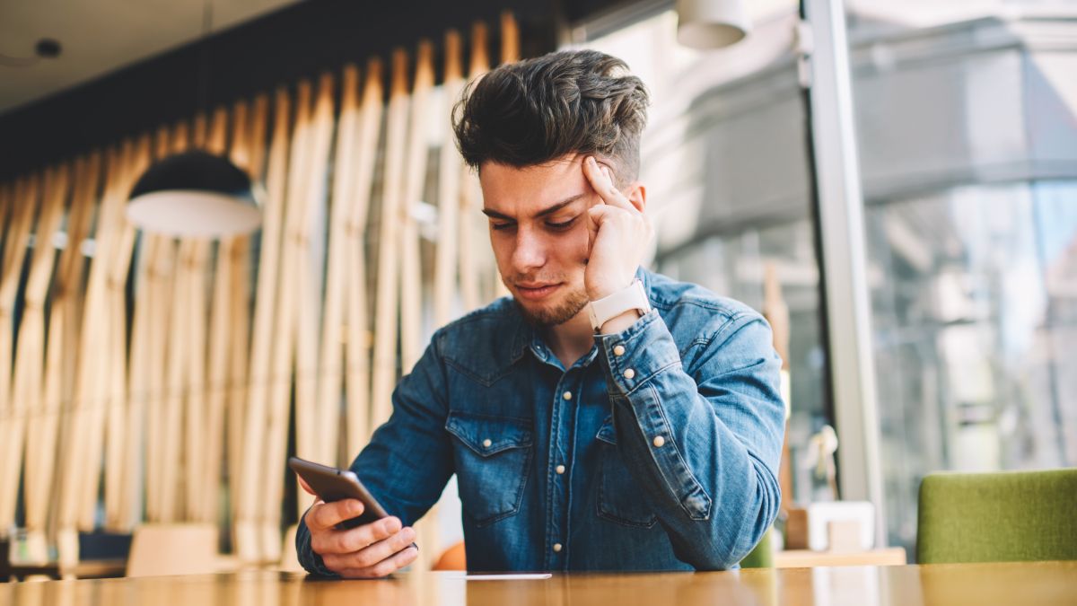 Man looking at his phone with stressed expression.
