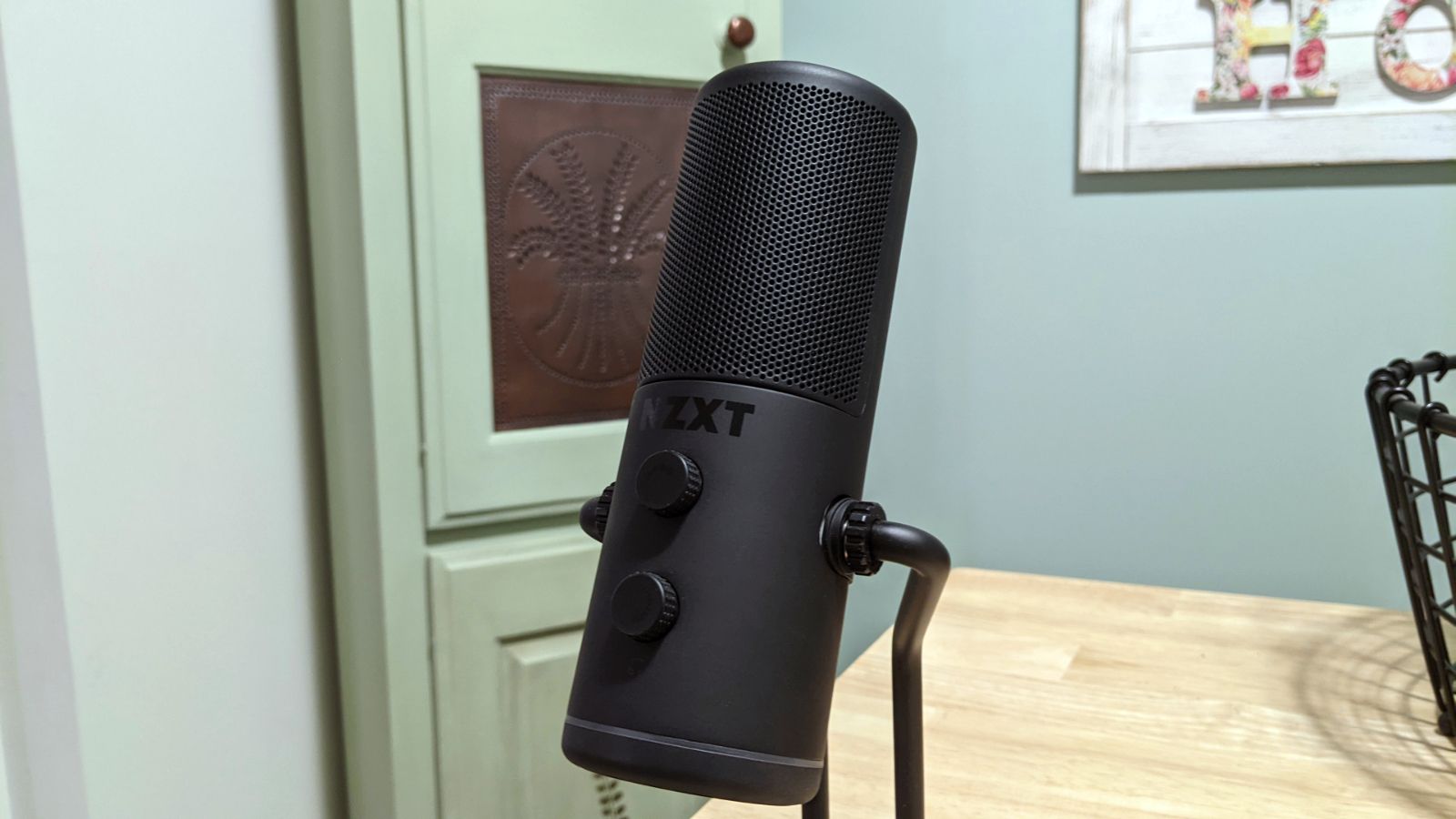 NZXT Capsule microphone on its stand in front of cabinet
