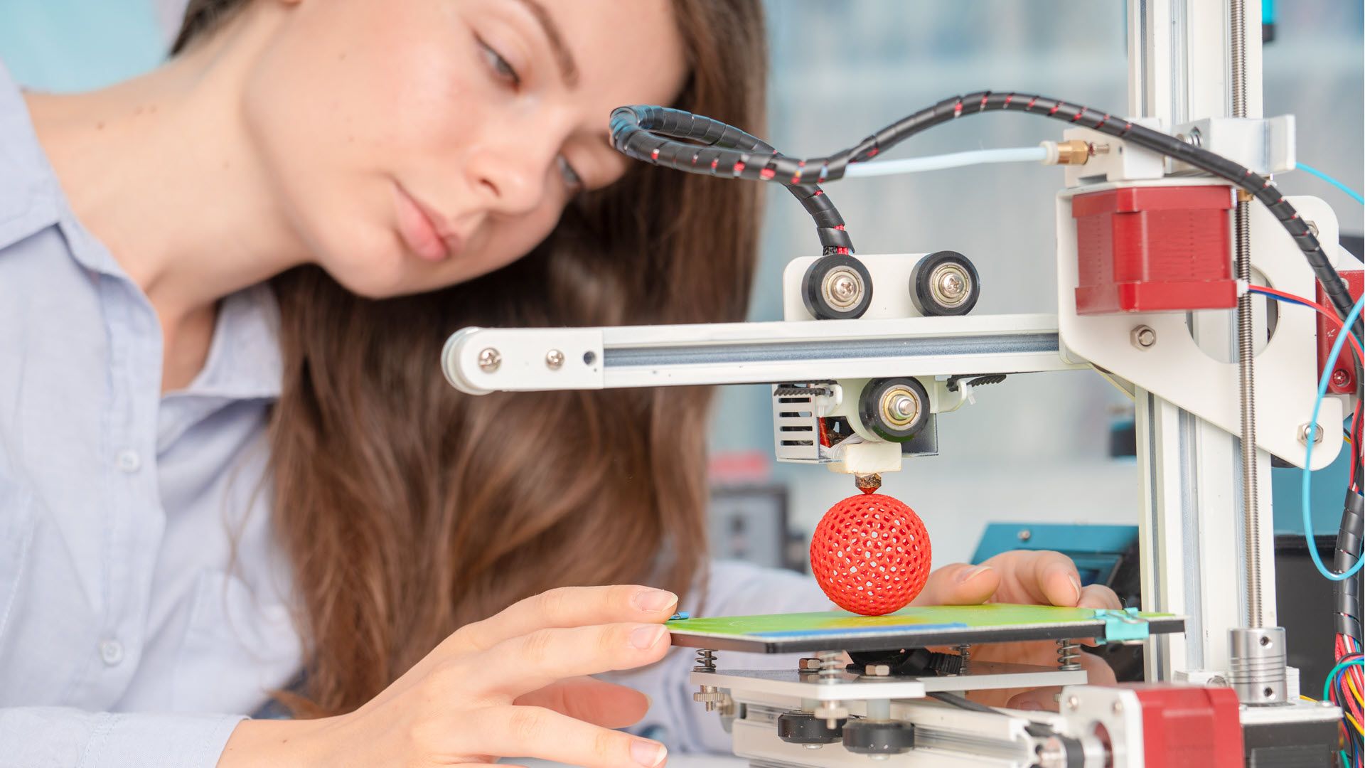 A woman looking at a 3D print in process.
