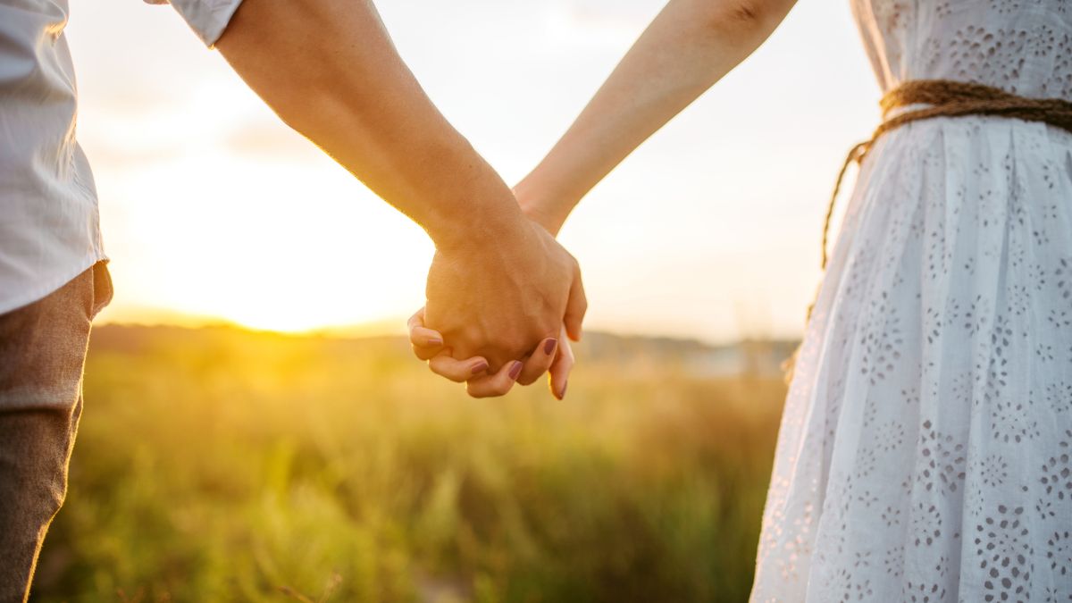 Closeup of couple holding hands at sunset