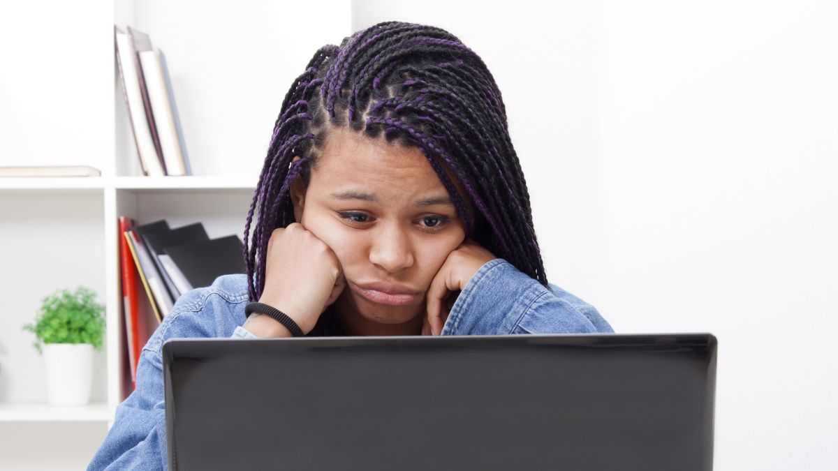 Woman looking at a laptop screen with tired look on her face.