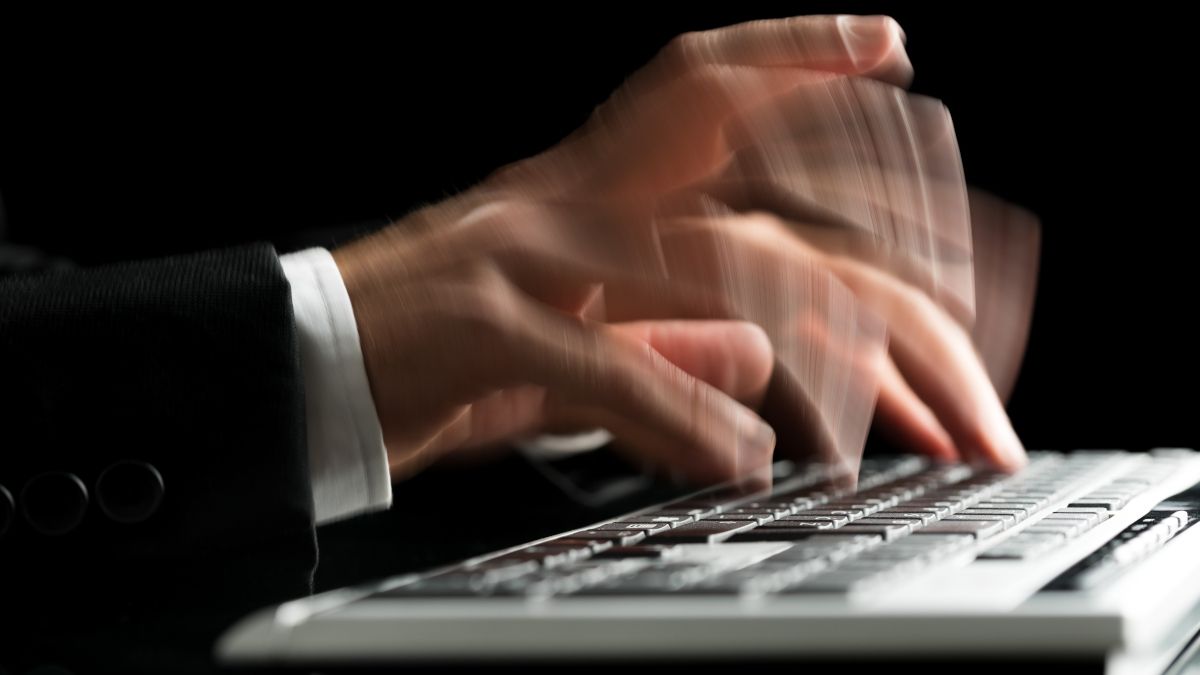 Close up of hands typing fast on a computer keyboard