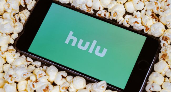 The Hulu logo on a smartphone screen surrounded by popcorn.