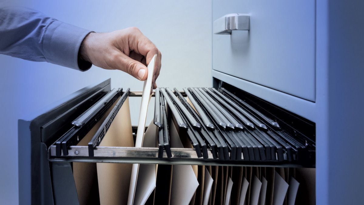 A hand pulling a file from a file cabinet.
