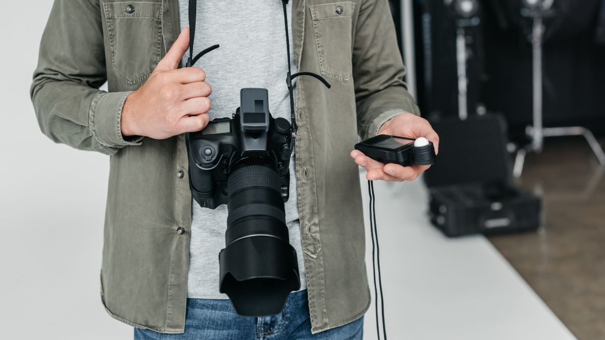 Photographer using a light meter in photo studio
