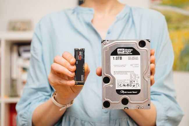 Woman holding an NVME drive and HDD.