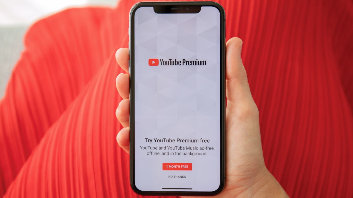 Hand holding smartphone showing YouTube Premium sign up page