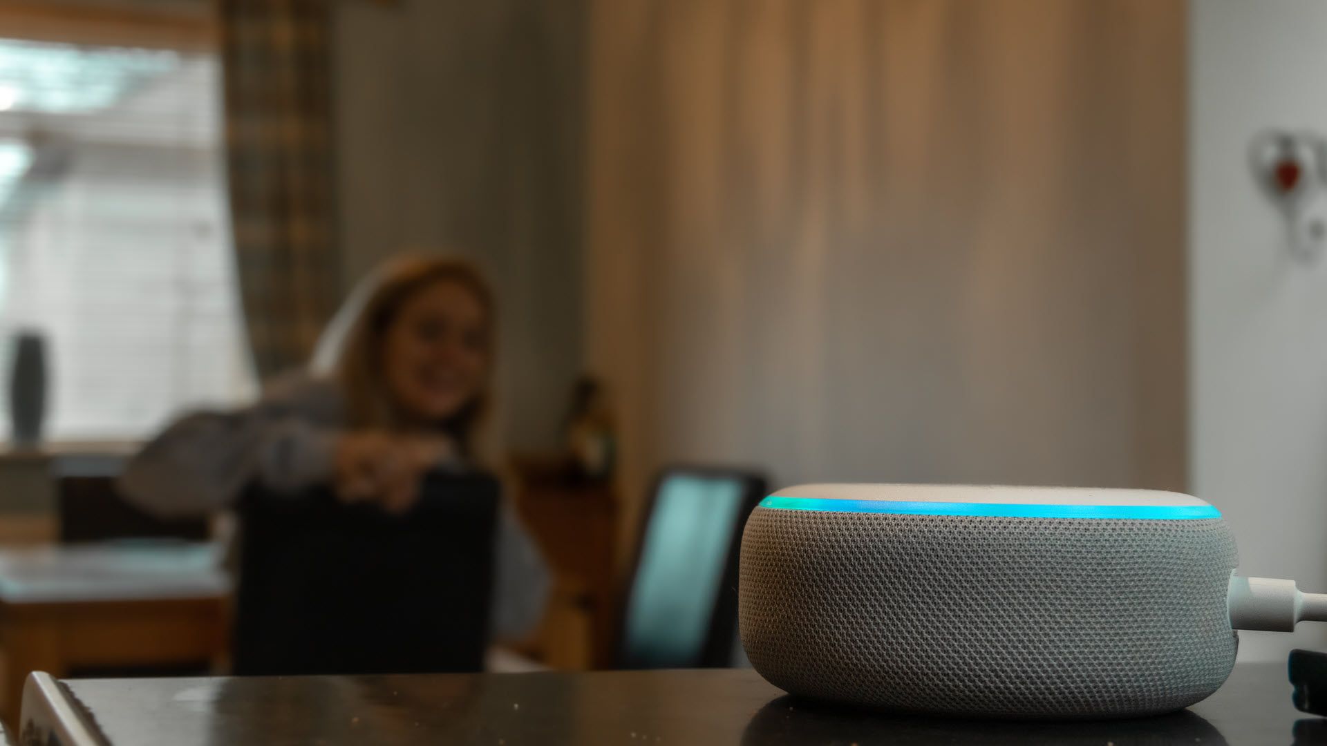 A woman talking to an Amazon Echo dot while frowning.