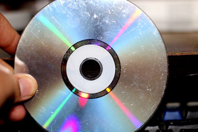 Hand holding a dirty and scratched compact disc