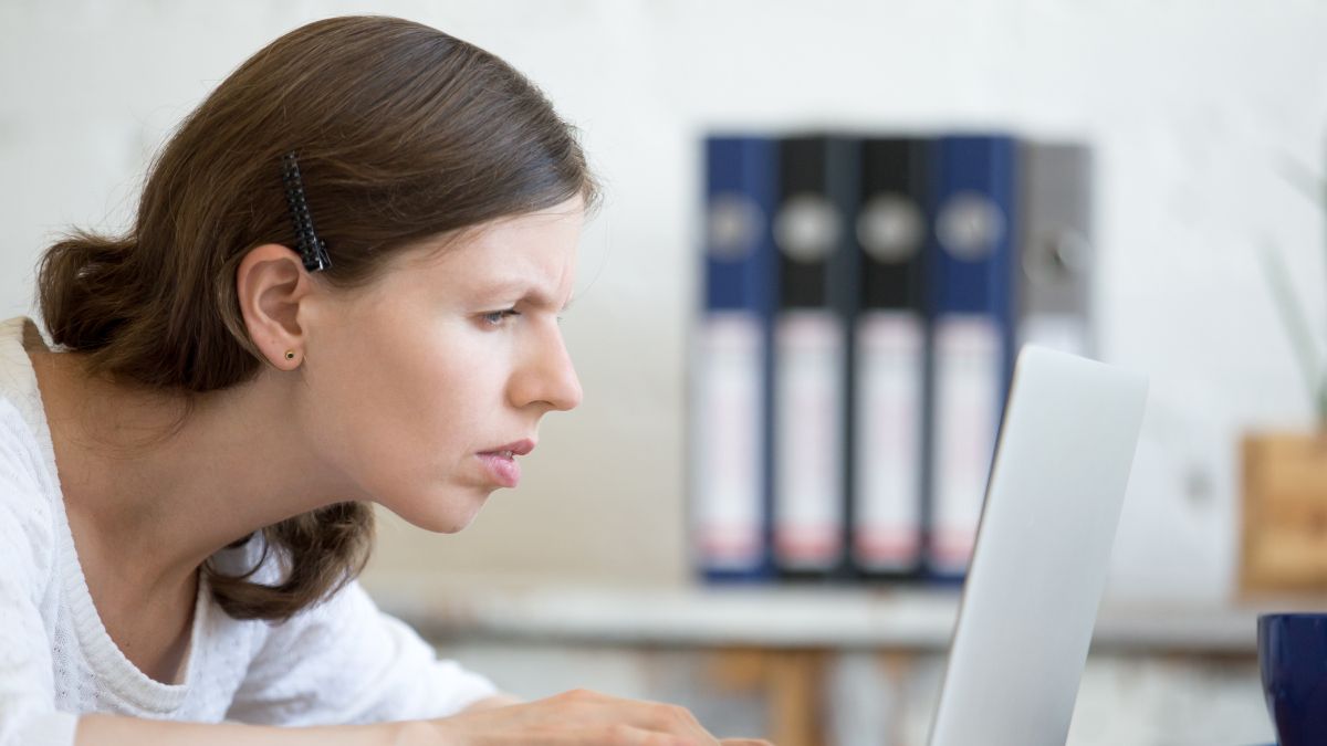 Woman looking with a stressed or focused expression at a laptop screen