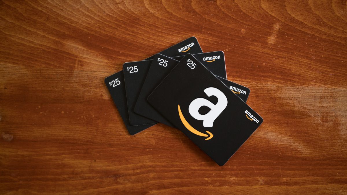Four Amazon gift cards on a wood surface