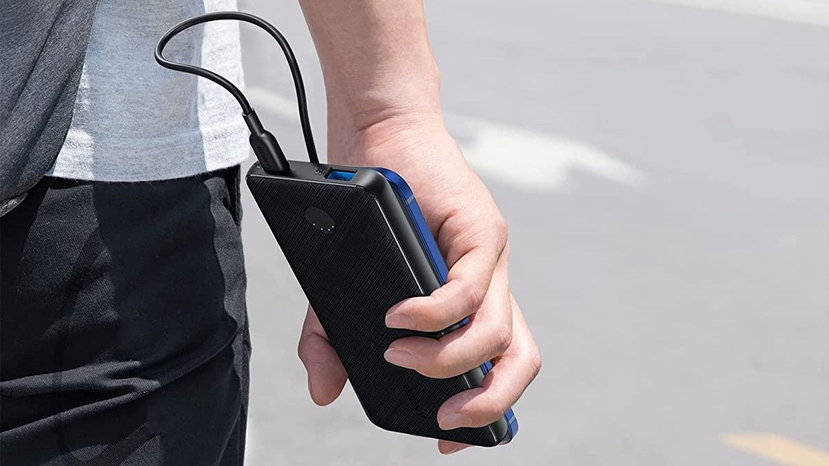 Person holding Anker charger with phone plugged in