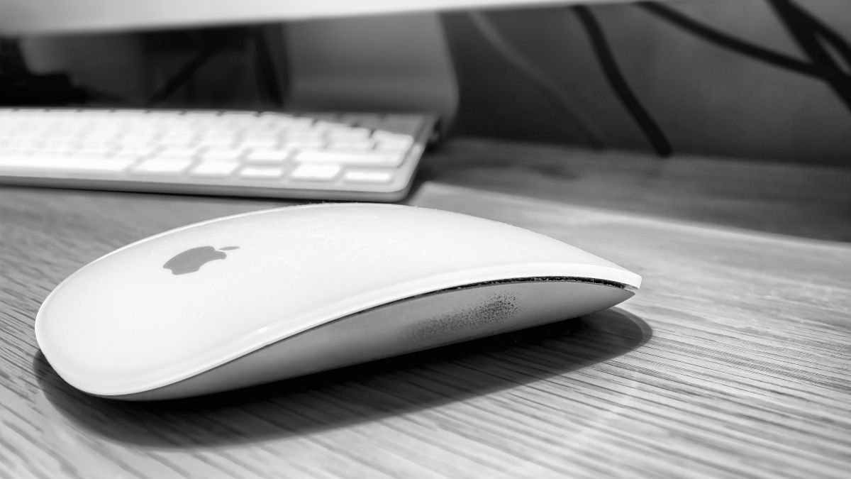 Apple Magic Mouse on a desktop next to a keyboard.