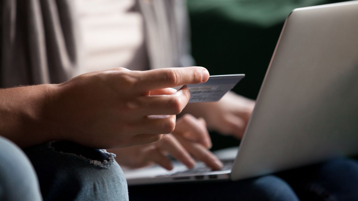 Couple shopping online with laptop and holding up credit card