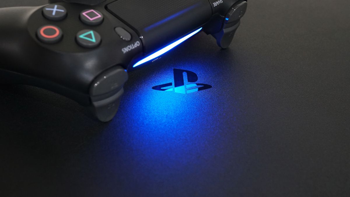 PlayStation logo on a PS4, in blue light cast by a controller