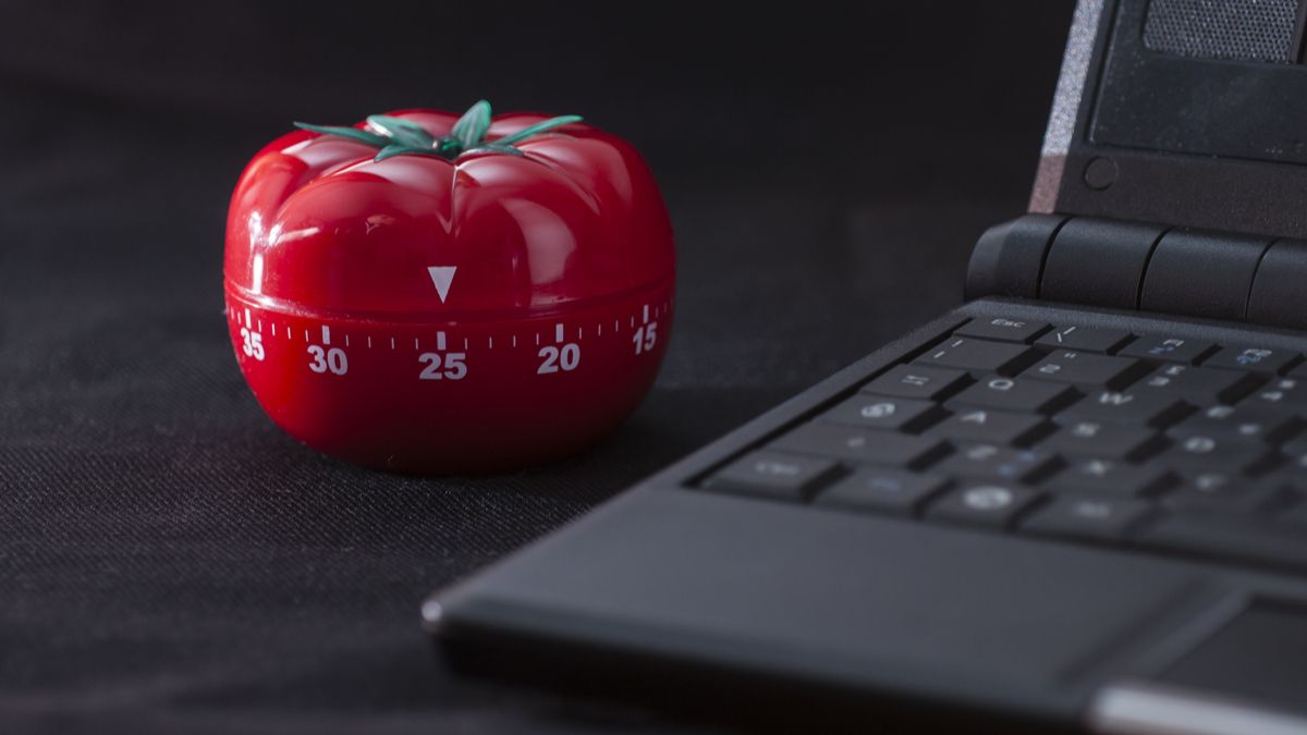 A classic Pomodoro timer next to a laptop