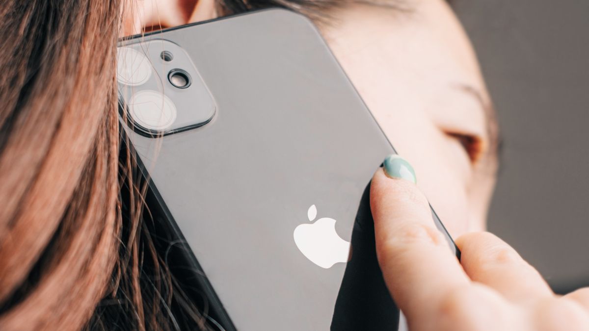 Closeup of a black iPhone 11 pressed to woman's ear