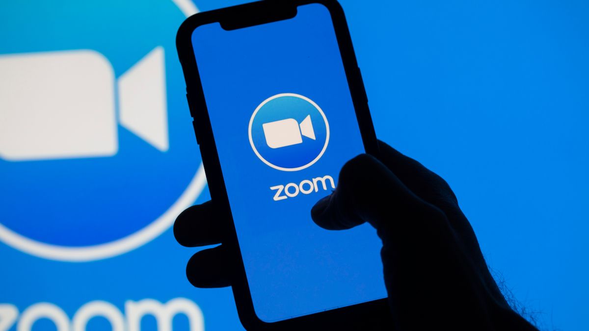 Smartphone showing Zoom logo over a larger Zoom logo backdrop