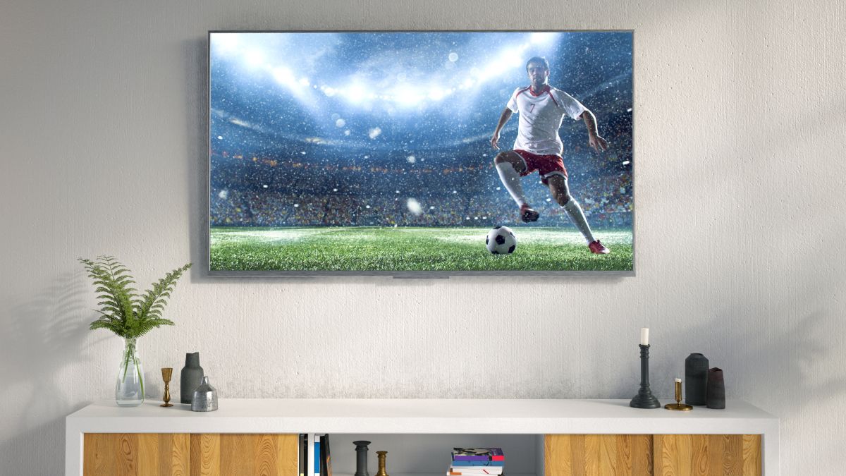 An LED TV hanging on the wall of a living room, with a soccer player onscreen.