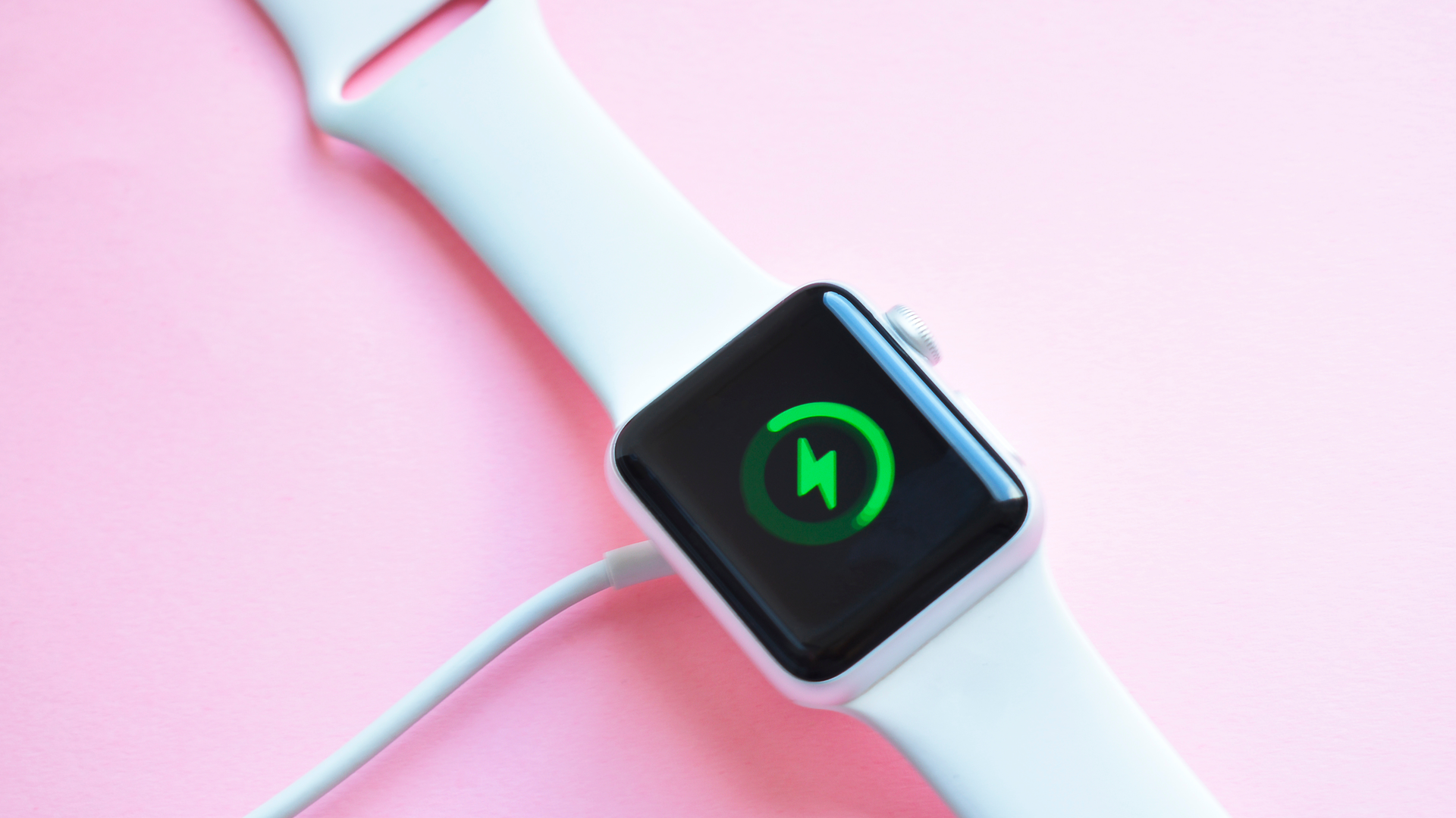 Charging an Apple Watch with a white silicon band.