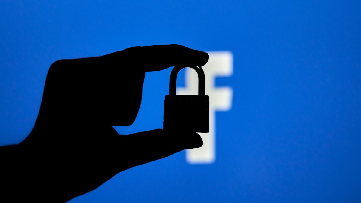 Silhouette of a hand holding a locked padlock over the Facebook logo