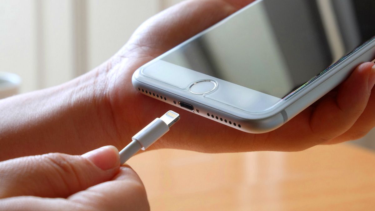 A person plugging a cable into an iPhone Lightning port.