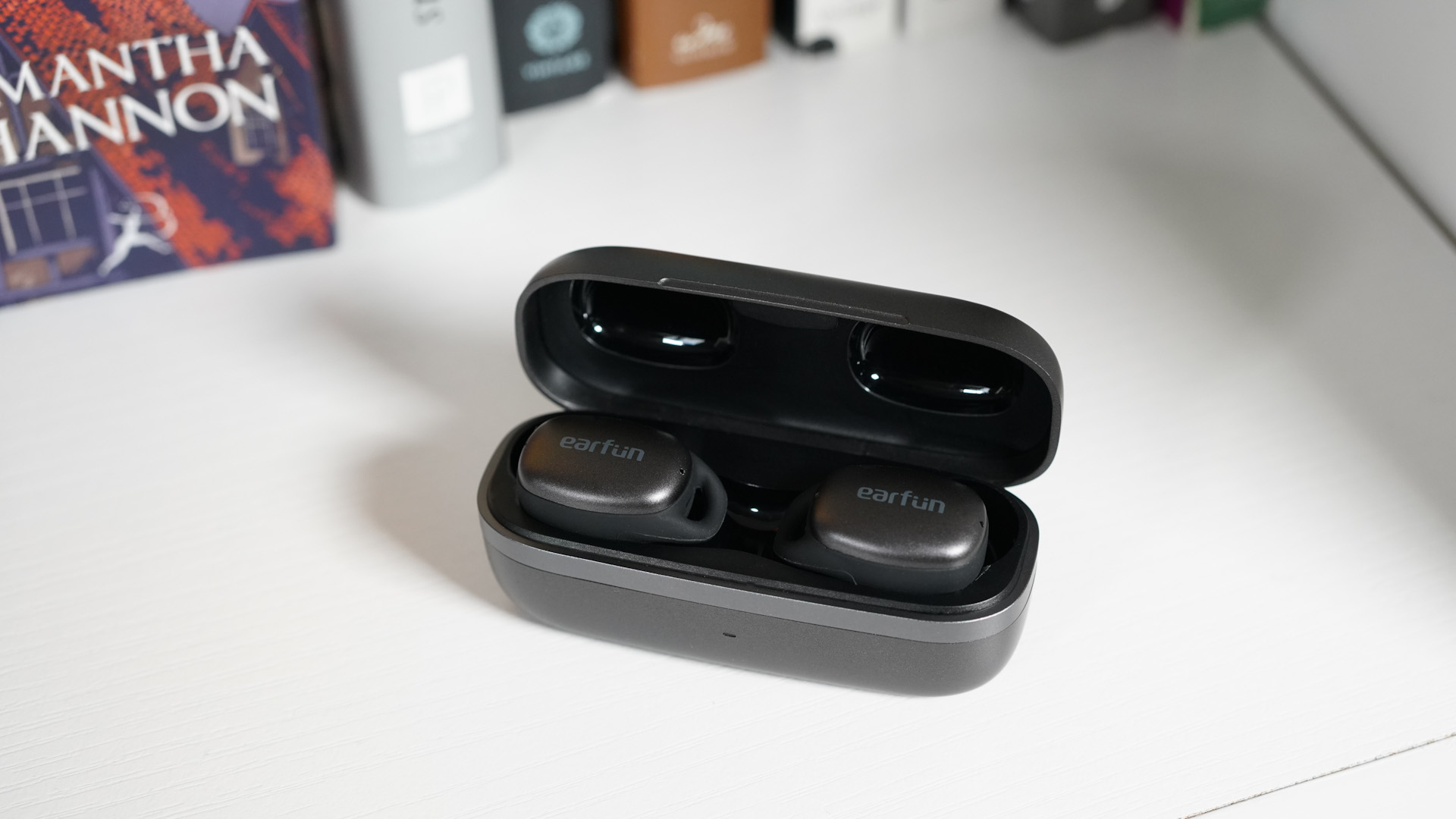 EarFun Free Pro 2 buds in their case with the lid open, on a bookshelf