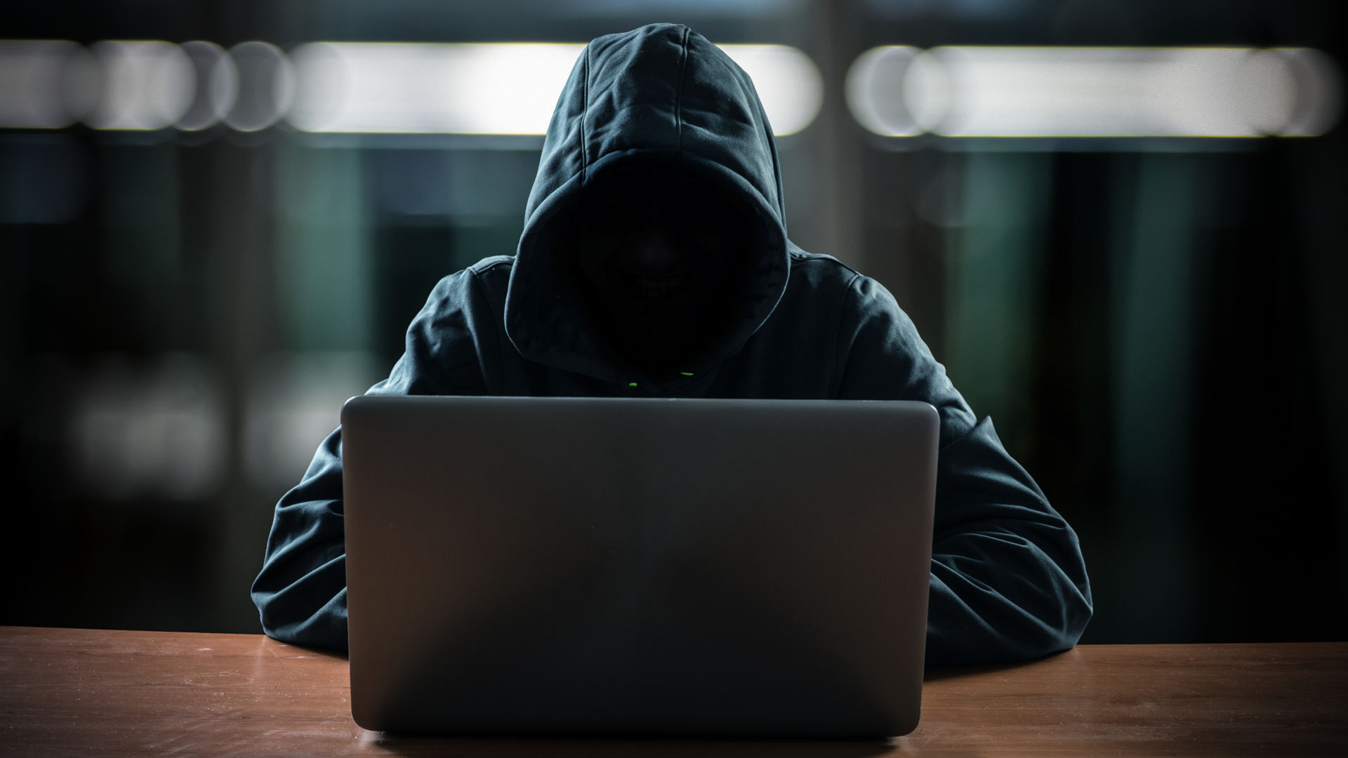 Hacker in front of his computer. Dark face.