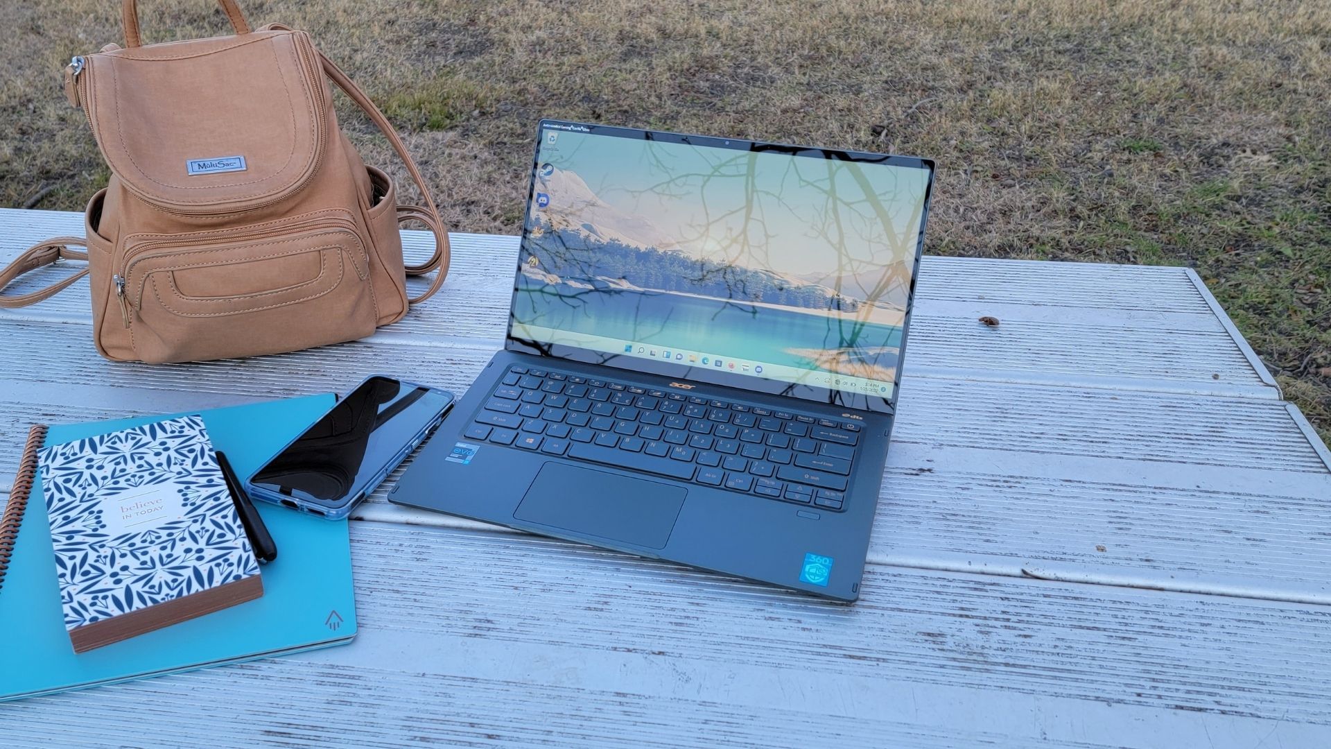 acer swift 5 review picture, the laptop on a metal table with a lake background saver
