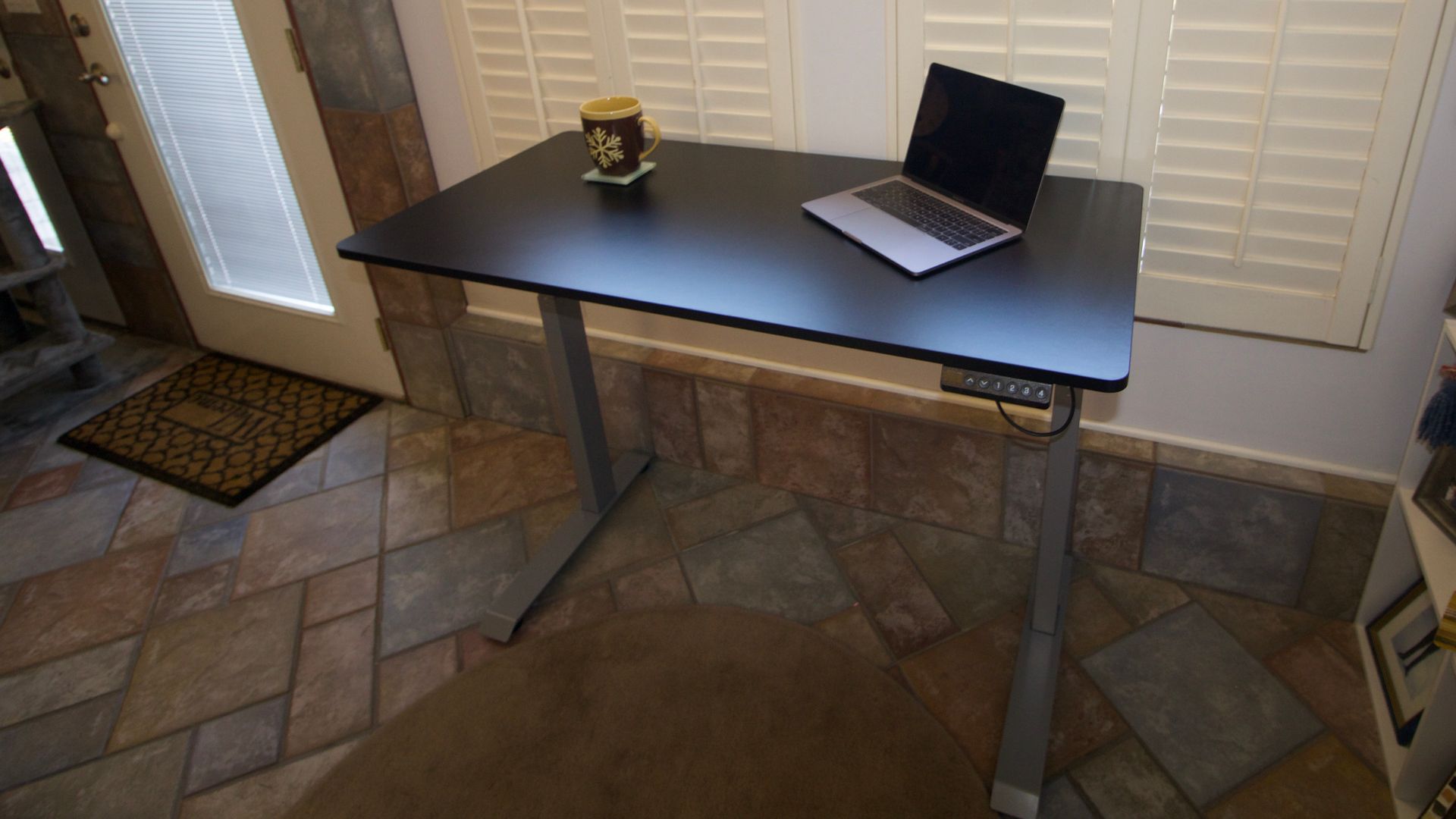 Victor High Rise desk with a laptop and coffee mug on the surface.